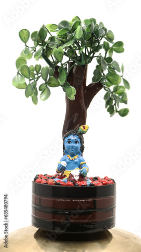Fotografie a colorful doll statue of cute baby sri krishna in blue eating butter out of a p
