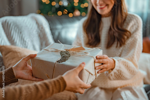 Excited asian woman getting surprise gift from her girlfriend at home. Gives a Christmas gift, birthday gift, New year day celebration and congratulation photo