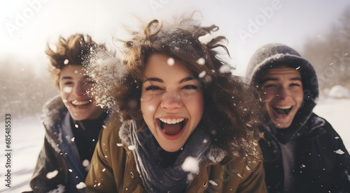 Close-up of friends' faces laughing with joy while playing in the snow.