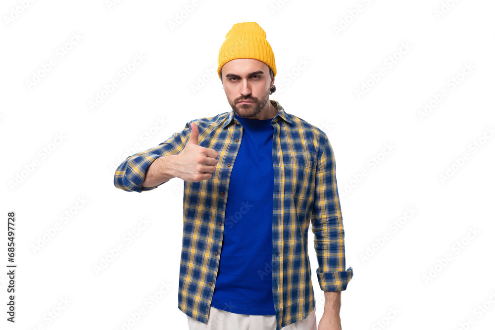 a young brutal brunette man with a beard and mustache in a shirt and cap shows class