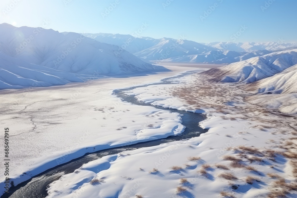 Aerial View of a Meandering River Through a Snowy Landscape with Mountain Ranges