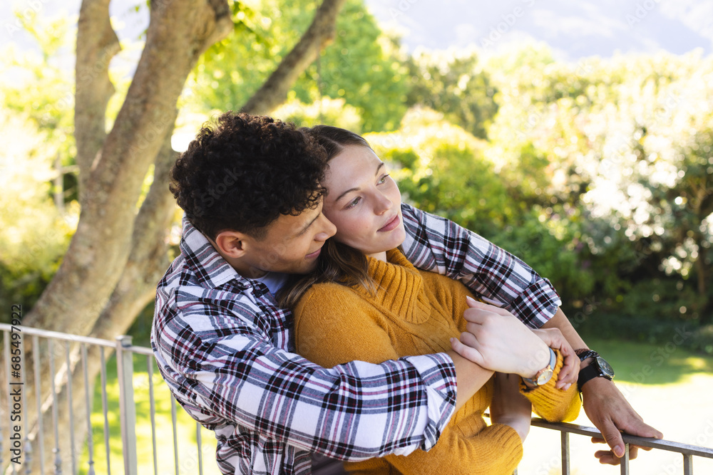 Happy diverse couple embracing and looking side in sunny garden, copy space Happy diverse couple embracing and looking side in sunny garden, copy space