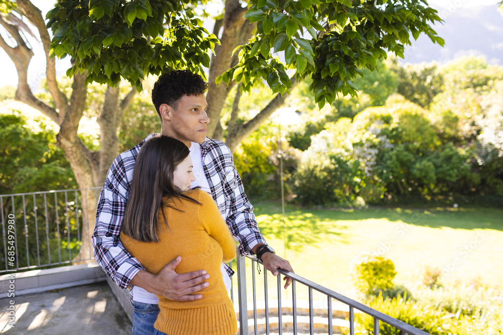 Happy diverse couple embracing and looking side in sunny garden, copy space Happy diverse couple embracing and looking side in sunny garden, copy space