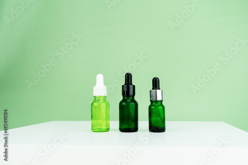 Set of realistic glass bottles with dropper Serum dropper bottle on green background