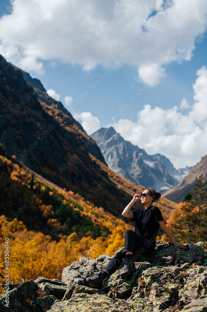 a girl with a backpack stands in the autumn mountains