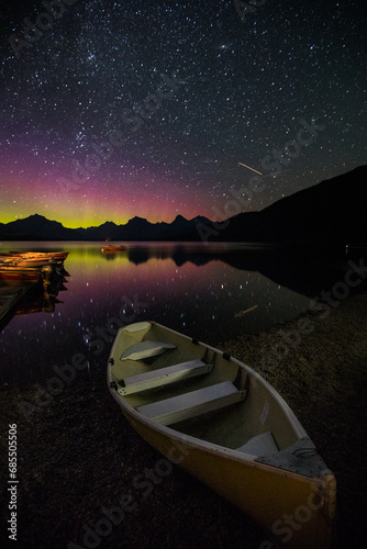 boats on lake at night with northern lights reflection 