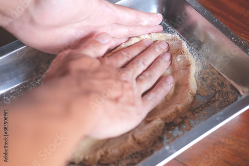 Hands of man kneading dough while making bread in the kitchen	