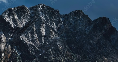 Beautiful right to left aerial slow speed 7x zoomed 4k mountain view of Austrian Alps. High quality prores footage in daylight with shadows from clouds, rocky steep hill with contrasting snow photo