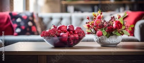 Fototapeta Naklejka Na Ścianę i Meble -  Red fruits and flowers in a bowl on a wooden coffee table in an elegant living room with a ginger sofa.
