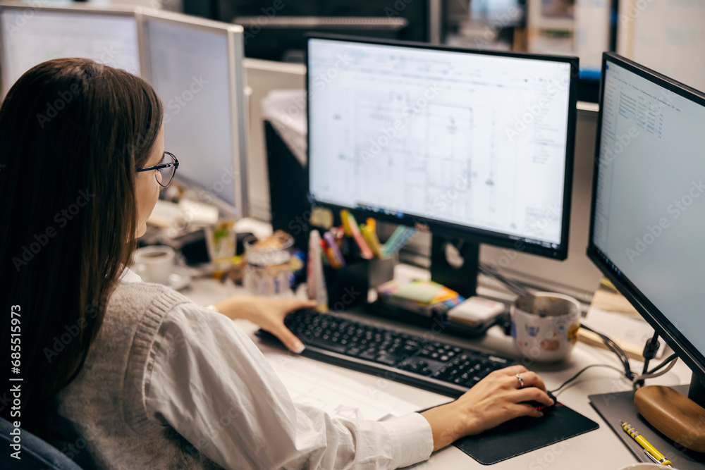 © dusanpetkovic1 - Rear view of a female architect working on blueprints at the office. © dusanpetkovic1 - Rear view of a female architect working on blueprints at the office.