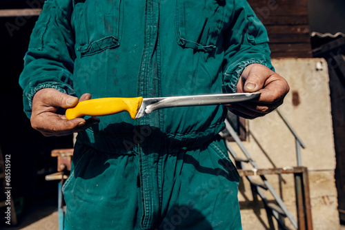 Cropped picture of cutler showing sharpened knife in front of his shop. photo