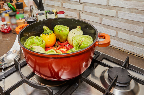 Stuffed zucchini and peppers are cooked in a saucepan on a gas stove photo