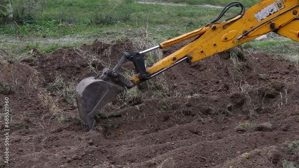 excavator bucket scoop removes the top layer of soil and levels it ...