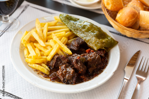 Appetizing stewed beef in red wine served with fries and baked green pepper..
