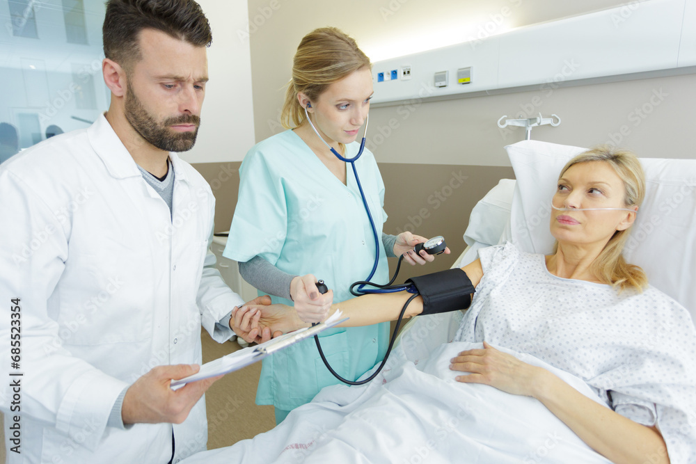 Obraz premium doctor and nurse taking blood pressure of senior woman