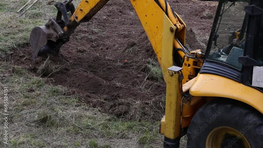 excavator bucket scoop removes the top layer of soil and levels it close-up.