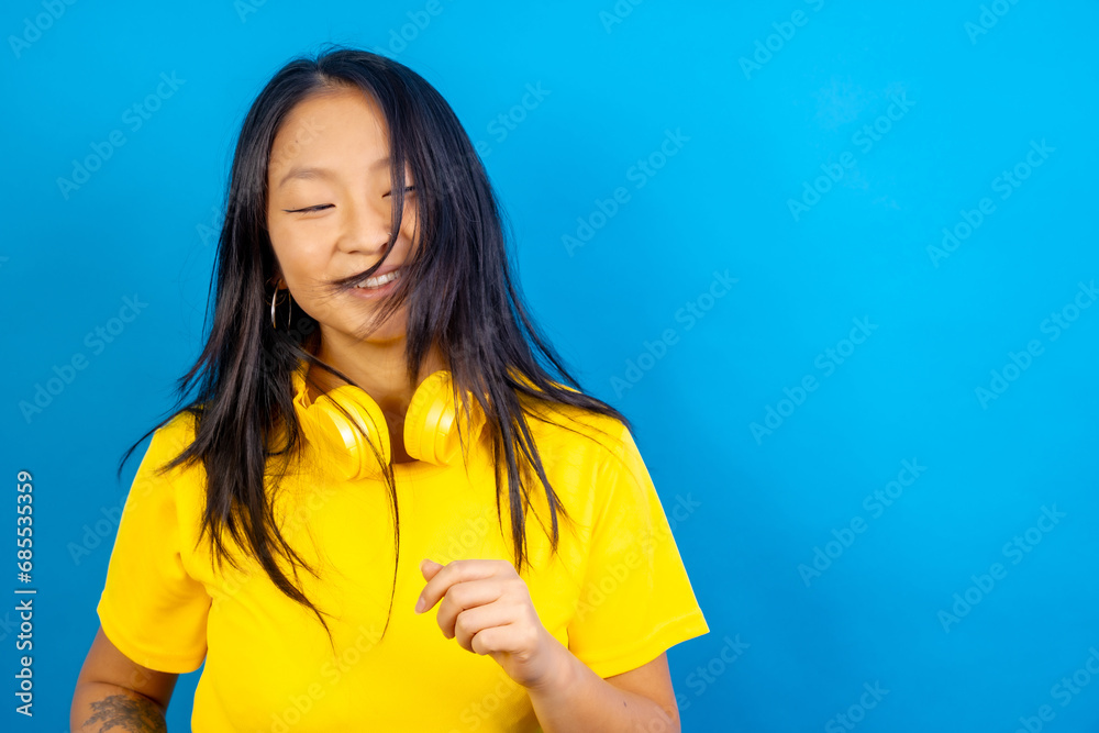 Young casual happy chinese woman with headphones dancing Young casual happy chinese woman with headphones dancing