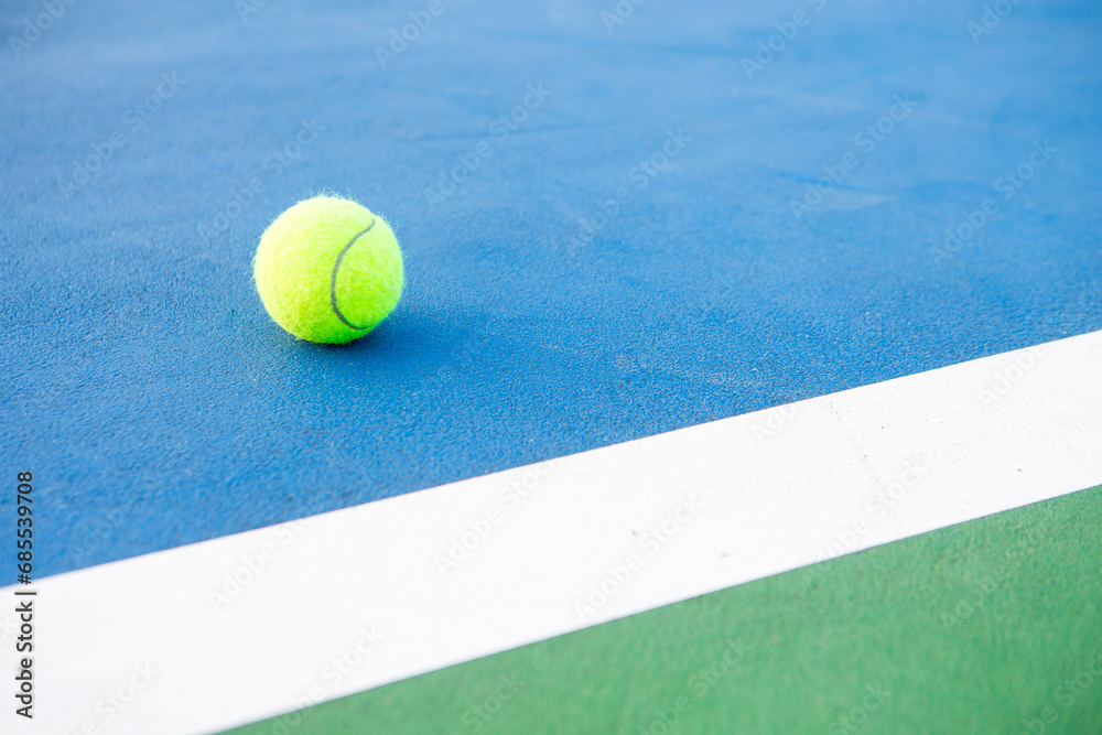 Tennis ball on a blue paddle tennis court.