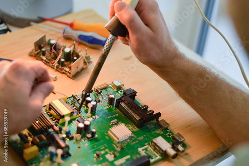 a master with a soldering iron soldering a chip, the concept of data, hardware, technician and technology.