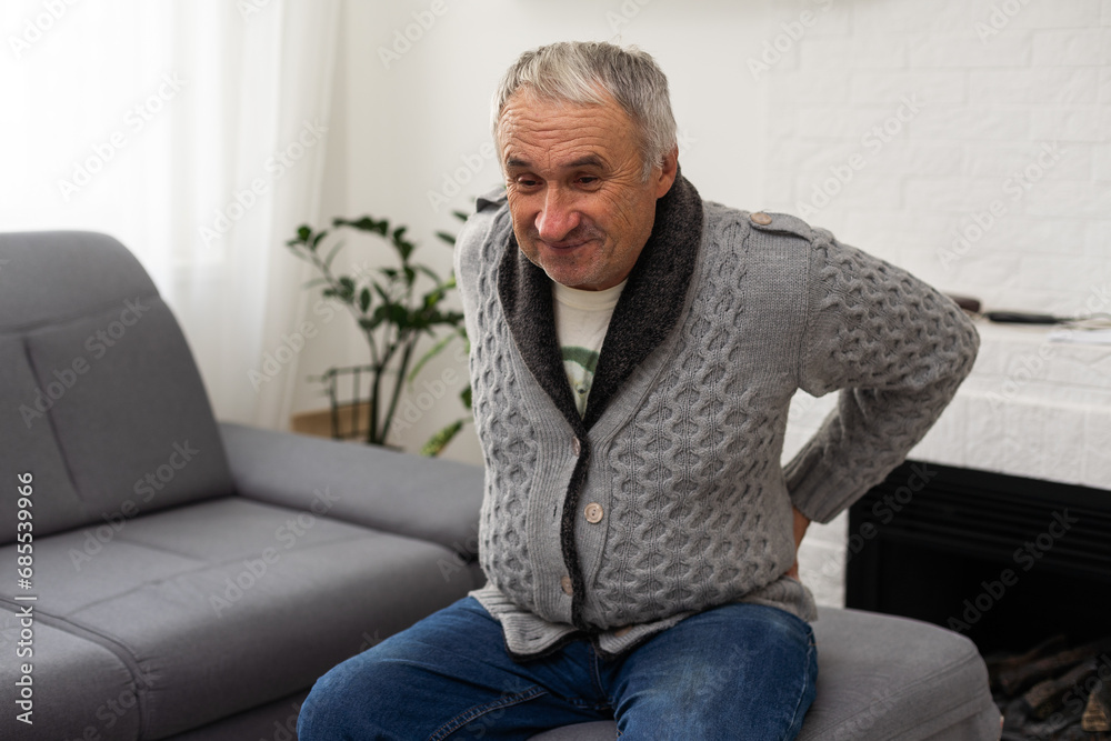 Senior man complaining of back pain in the room