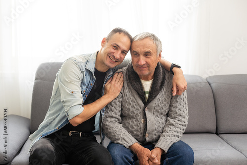 Portrait of grandfather and his teen grandson smiling. Isolated white background