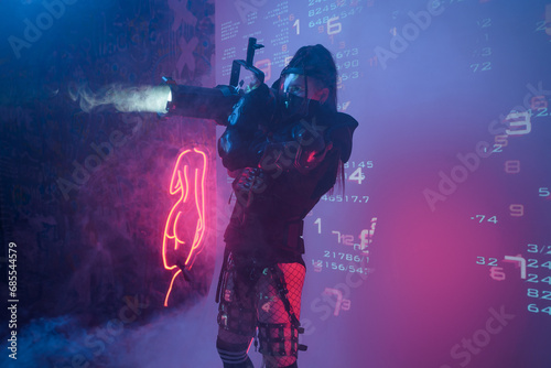 A woman in a futuristic tactical black suit holds a large projector resembling a light cannon, standing against a backdrop of projected digital symbols