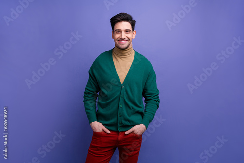 Photo of cheerful handsome man dressed green outfit hands in pockets isolated on purple color background