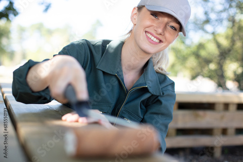attractive young woman painting a table outdoors © auremar