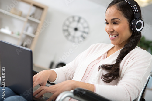 happy disabled woman in wheelchair at home with tablet pc