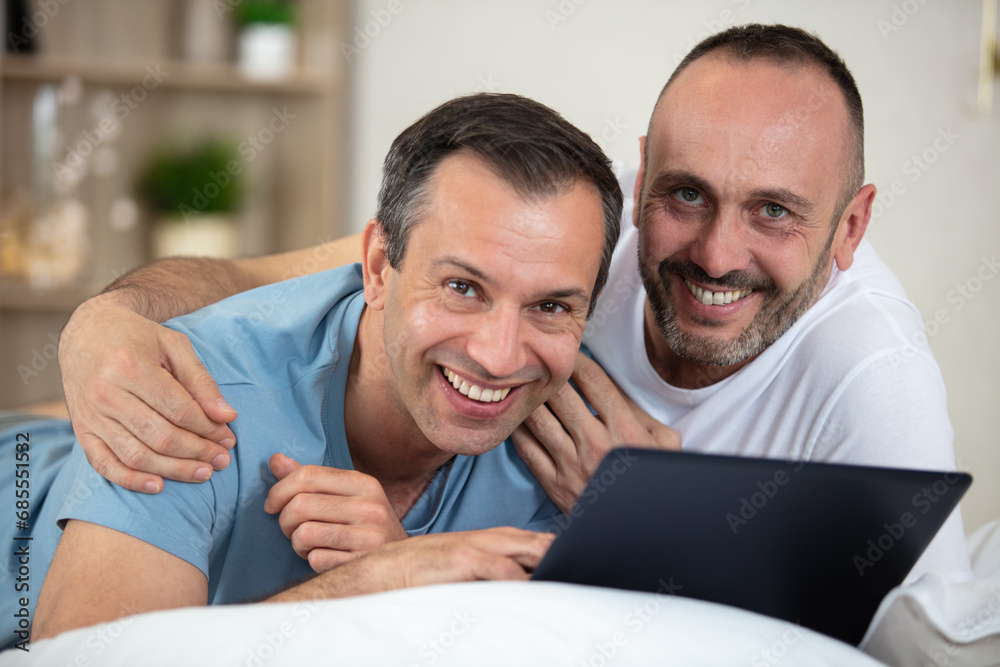homosxual couple streaming movie on laptop computer in bed homosxual couple streaming movie on laptop computer in bed