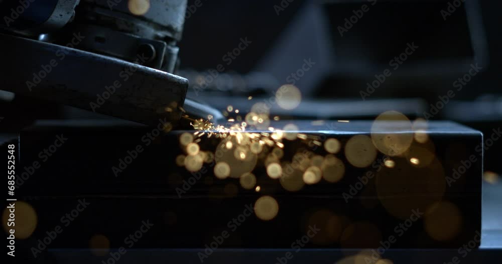 Super slow motion macro of blacksmith welder is smoothing metal steel with industrial angle grinder with flying sparks in workshop.