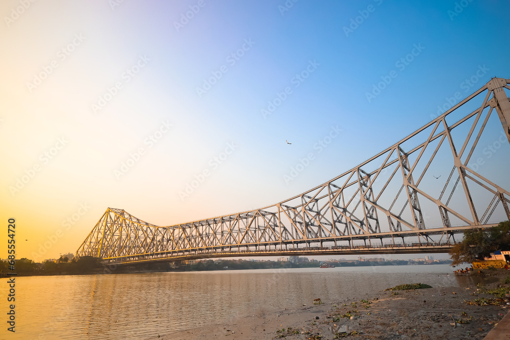 Obraz premium Historic Howrah bridge Kolkata at sunset with blue sky.
