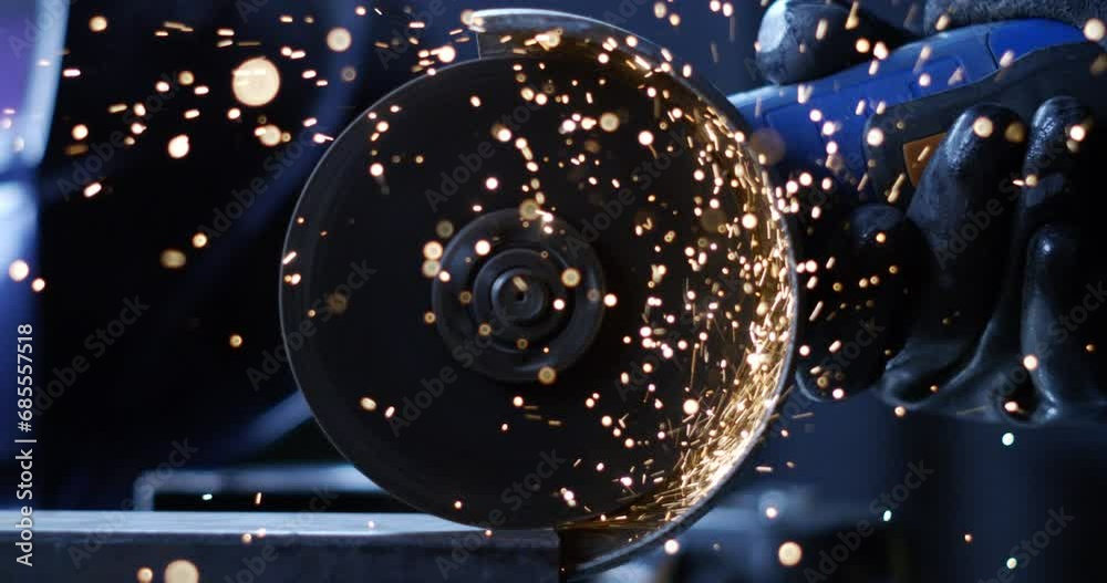 Super slow motion close up of blacksmith welder is smoothing metal steel with industrial angle grinder with flying sparks in workshop.
