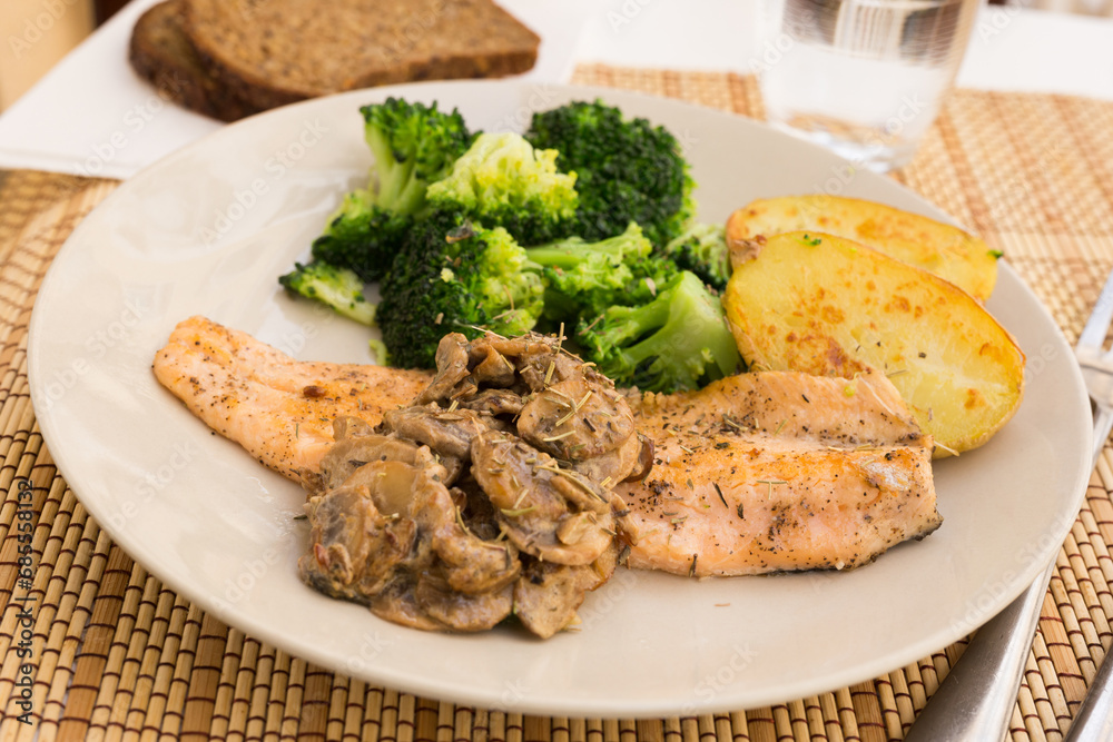 Fried river trout fillet with a complex side dish of broccoli, baked potatoes and mushroom sauce Fried river trout fillet with a complex side dish of broccoli, baked potatoes and mushroom sauce