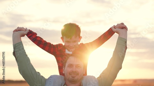 Father carries son on shoulders at back sunset on family vacation in countryside