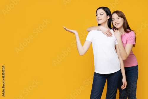 Two sisters pose on a yellow background