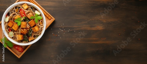 Top view of a bowl with soba noodles vegetables and fried tofu copy space image