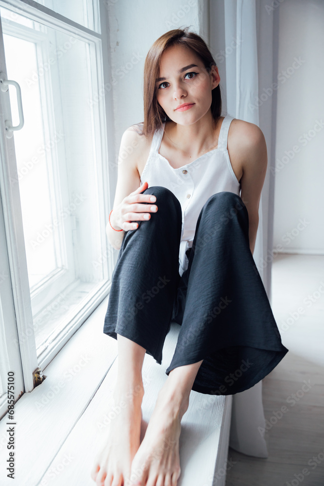 Portrait of a beautiful fashionable woman at the window in a white room Portrait of a beautiful fashionable woman at the window in a white room