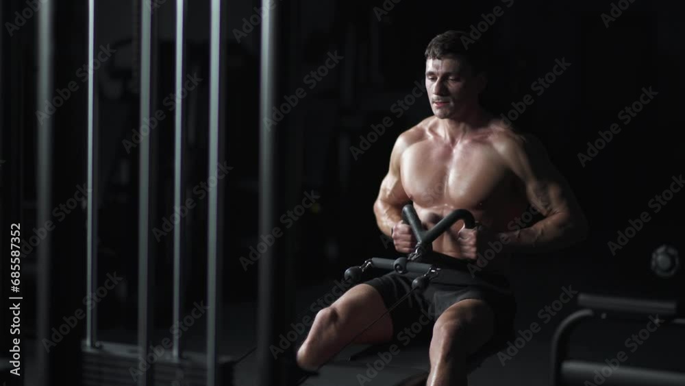 Athletic man in the Gym lifting blocks on rowing machine, hard training on block device and gym equipment, night training, cinematic light. Athletic man in the Gym lifting blocks on rowing machine, hard training on block device and gym equipment, night training, cinematic light.