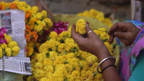 Marigold flowers in the market, Women Sting Marigold Garland for Decoration - Flower Seller in India photo