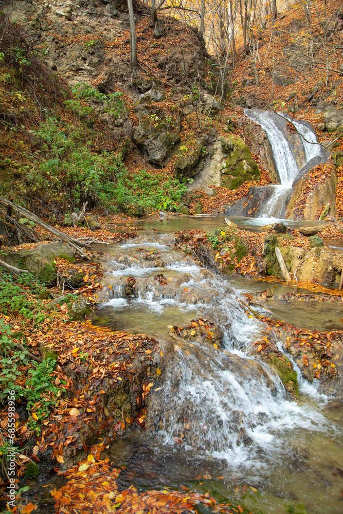 Beautiful view of small waterfall in autumn forest.