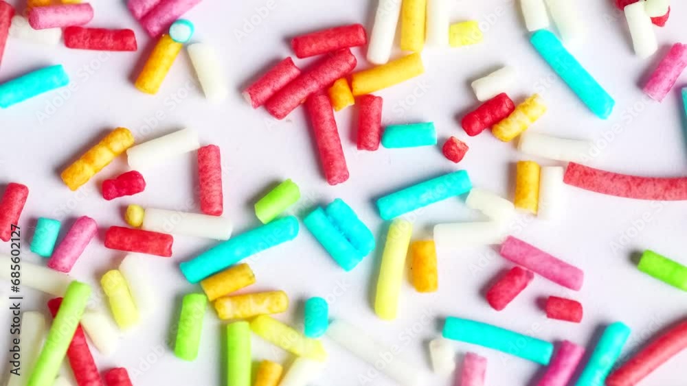 Sweet sugar sprinkles on white background, macro video. Multicolored sprinkles rotation. Sweet sugar sprinkles on white background, macro video. Multicolored sprinkles rotation.