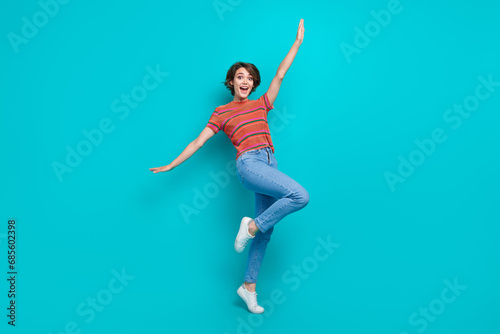 Full length photo of positive cheerful glad woman dressed stylish clothes raise hands celebrate holiday isolated on cyan color background