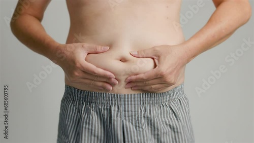 close up of man hand pinching excessive belly fat photo