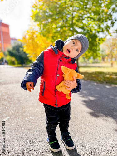 A Young Boy in a Red Jacket Holding a Stuffed Animal. A young boy in a red jacket holding a stuffed animal