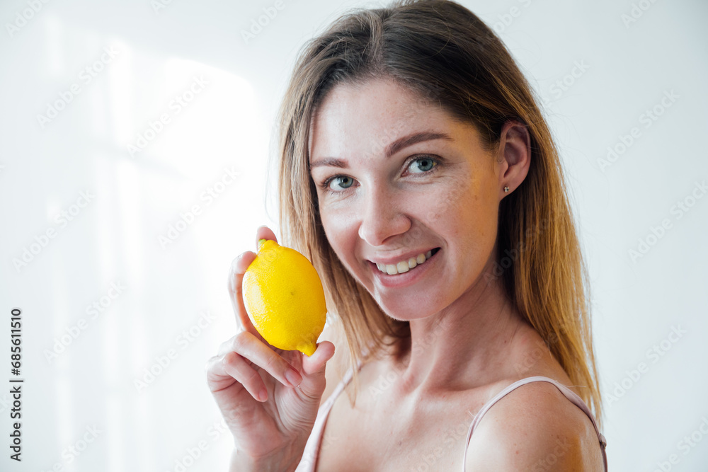 Beautiful woman holding yellow lemons and smiling