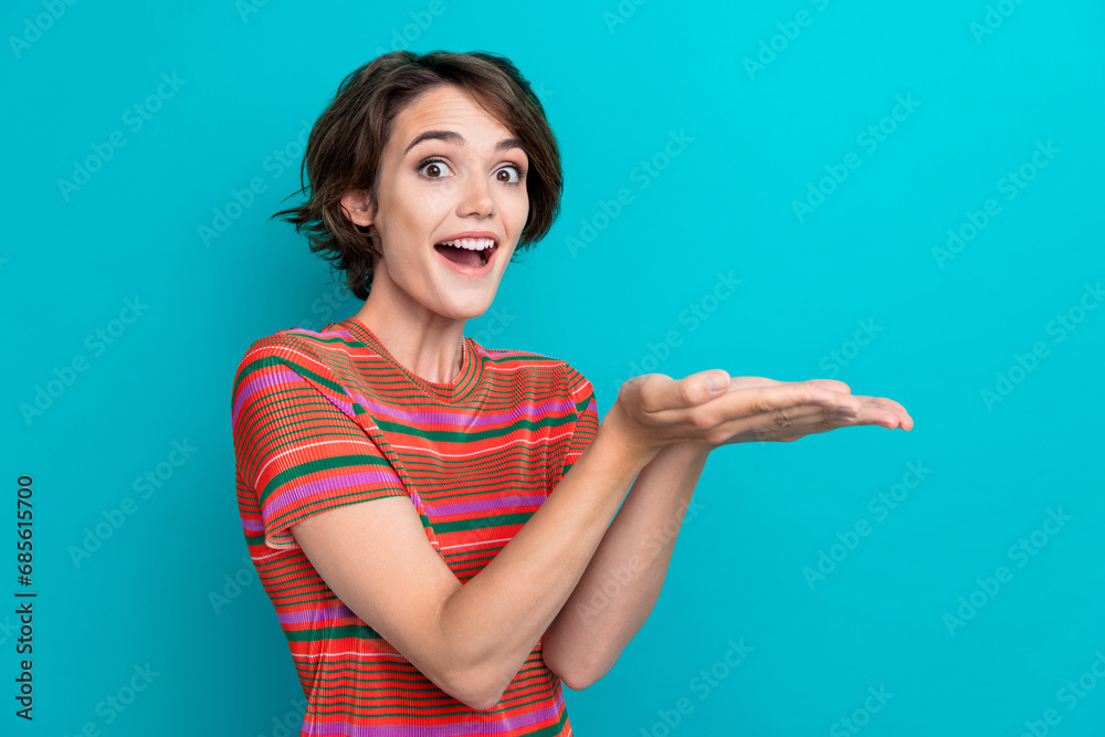 Portrait of impressed ecstatic girl wear stylish t-shirt palms demonstrate object empty space isolated on turquoise color background Portrait of impressed ecstatic girl wear stylish t-shirt palms demonstrate object empty space isolated on turquoise color background