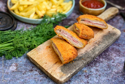  Crispy  deep fried home made     chicken Cordon bleu with cheese   and ham  and french fries on wooden rustic background.   photo