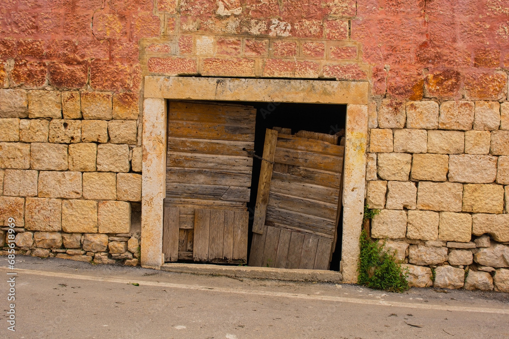 An old wooden door in an historic abandoned stone house in Milna Village on the west coast of Brac Island in Croatia An old wooden door in an historic abandoned stone house in Milna Village on the west coast of Brac Island in Croatia