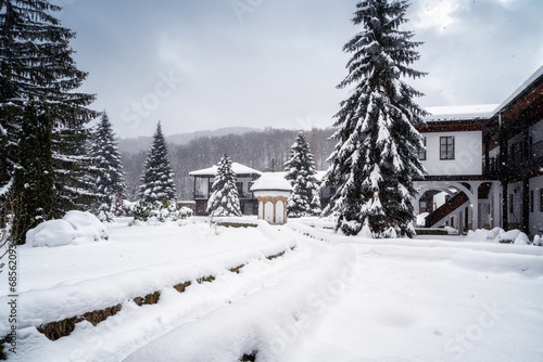 Amazing winter landscape with softly falling snow and thick snowdrifts in the courtyard of the Sokolski Monastery near Gabrovo, Bulgaria photo